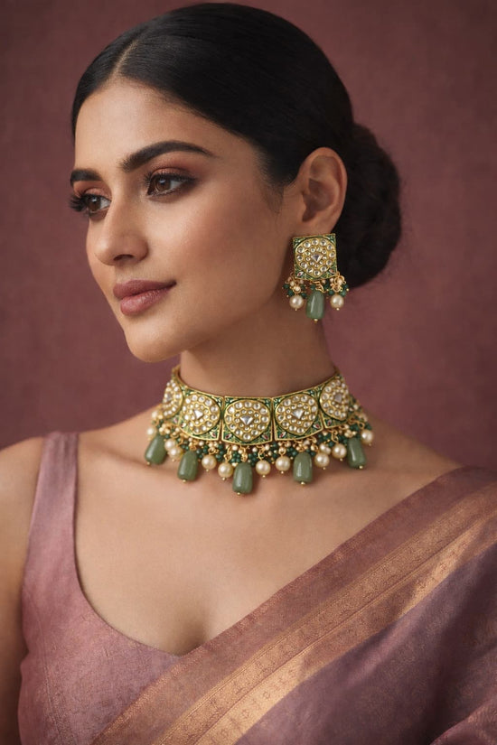 Woman wearing green and gold jewelry against a brown background